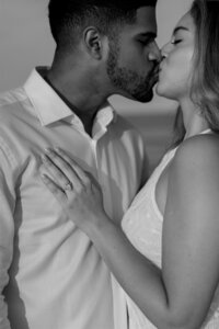 A newly engaged couple shares a kiss at Jetty Park Beach in Port Canaveral, showing off her engagement ring — captured by an Orlando Proposal Photographer.