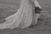 A slightly blurred photo of someone in a wedding dress walking on the beach