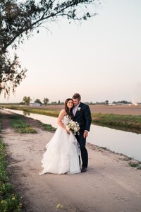 bride and groom posing next to river