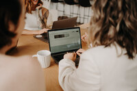 observing a meeting of girls with focus on a laptop in the middle of a table