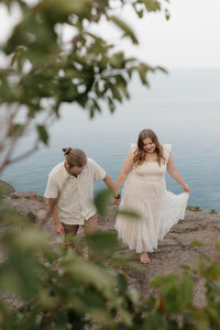 A couple holding hands and walking up a trail 