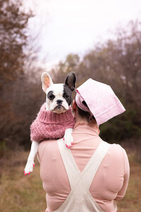 little dog wearing pink on girls shoulder
