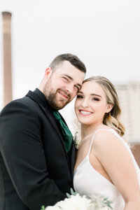 Bride and Groom smiling at the camera on a rooftop taken by Washington wedding photographer