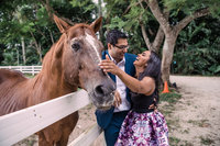 man & woman laughing and petting horse