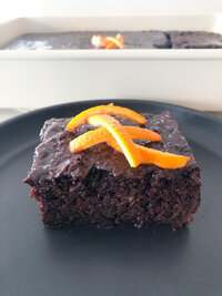 chocolate portokalopita on a black plate.