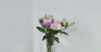 An assortment of lilies and roses in a clear vase.