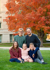 Family of five close together smiling at University of Iowa campus.