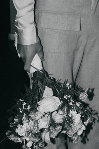Black and white image of a hand holding wedding flowers representing florist vendors at The Crush Collective wedding expo.