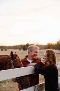 A couple standing on either side of a fence smiling at each other