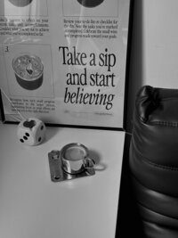 Black and white phot of a metal coffee cup, on a light colored table, with a magazine like graphic in a dark-colored photo frame. Rodeo PR website graphics