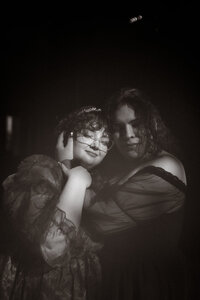 Moody black and white portrait of a queer couple in vintage-inspired attire, captured in an intimate and artistic wedding photography approach.