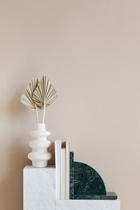 vase with palm branches in it on a bookshelf