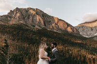 A couple holds hands with the alpenglow in the background at sunrise before their elopement starts.