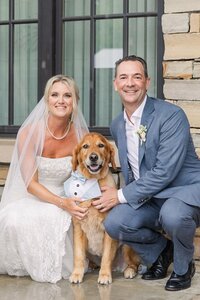 Bride and groom pose for wedding portrait with their dog