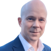 Jaime Hartles CEO with a Bald head in a dark suit jacket and white shirt, smiling at the camera.