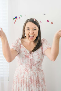 wedding photographer educator Katiera is throwing confetti in the air while smiling at the camera