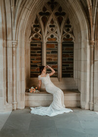 Bride in a fitted gown posing dramatically beneath gothic arches at Duke Chapel in Durham, North Carolina.