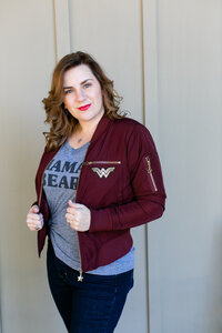 Susie Aguilar headshot with bright red lipstick and wonder-woman jacket