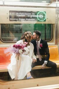 Newlyweds snuggled together sharing a kiss on a subway in NYC