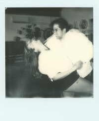 Black and white Polaroid of Javi dipping Dominique mid-laugh in their living room — a joyful, intimate glimpse into the film wedding photographer duo behind Castillo Holliday Photo + Film, known for analog wedding films and Super 8 wedding films.