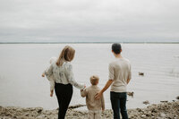 family holding hands beside water