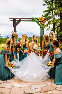 Julia Romano Photography Flagstaff Arboretum wedding bridesmaids holding dress florals on arch mountains