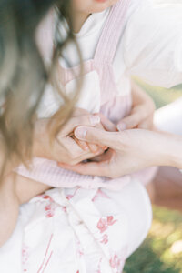 mom and dads hands wrapped around little one year old daughter's hand