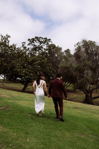 bride and groom holding hands, walking on hillside at destination wedding, elopement
