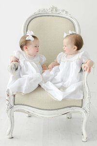 twins sitting in a large chair staring at each other during photo shoot