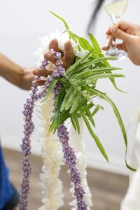 A person holding a white and purple lei 