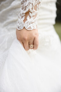 bride's hand with wedding band as she holds her train