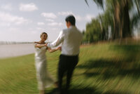 A motion blur photo of a wedding couple holding hands and running around in a circle.