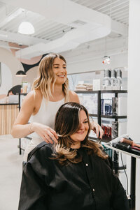 Stylist creating a fresh, low-maintenance hairstyle for a happy client at Salon Beau.