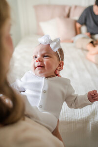 A newborn baby girl smiling at her mom during an in-home lifestyle family session in Gainesville, FL