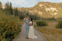 Wedding photography by Brittney Ann Photography. A bride and groom hold and look at each other with the mountains behind them.