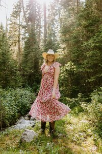 Senior session outdoors in Bozeman Montana, Arya swishes her dress while wearing a cowboy hat.