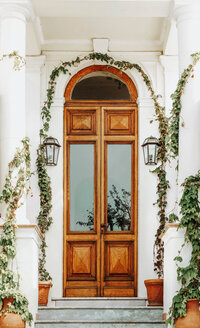Elegant wooden doorway framed by greenery inviting travelers to begin planning journey. Tailored Oasis Travel Co.
