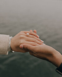 couple holding hands with water in the background