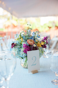 A table number with a floral bouquet on a reception table