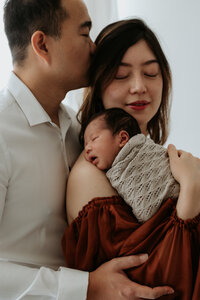 happy couple embracing their baby during newborn photography session