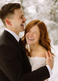laughing couple at their elopement  in snowy kelowna