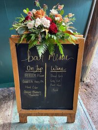 Floral arrangement by Springfield Oregon florist Flowers and Thyme sit atop a wedding welcome sign.