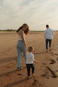 mom dad and son walk on beach for lifestyle family session in pei