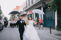 Bride and groom walk down the street with lace umbrellas in New Orleans