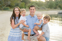 family of five in blue and white on the beach at golden hour 
