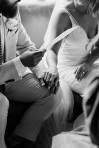 A bride and groom tenderly hold hands as they exchange vows during their wedding ceremony in Wellington, Prince Edward County