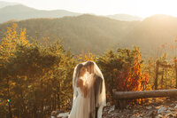 bride and groom standing under a veil at sunset
