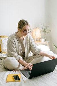 young girl sitting on bed on phone and computer