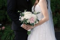 Bridesmaids wearing elegant black dresses holding white flwoer bouquets.