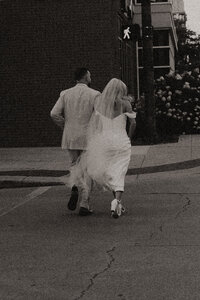 Couple running together after ceremony in black and white